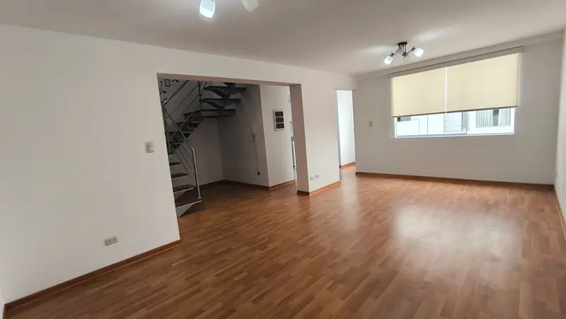 Sala amplia con escalera de caracol y piso laminado